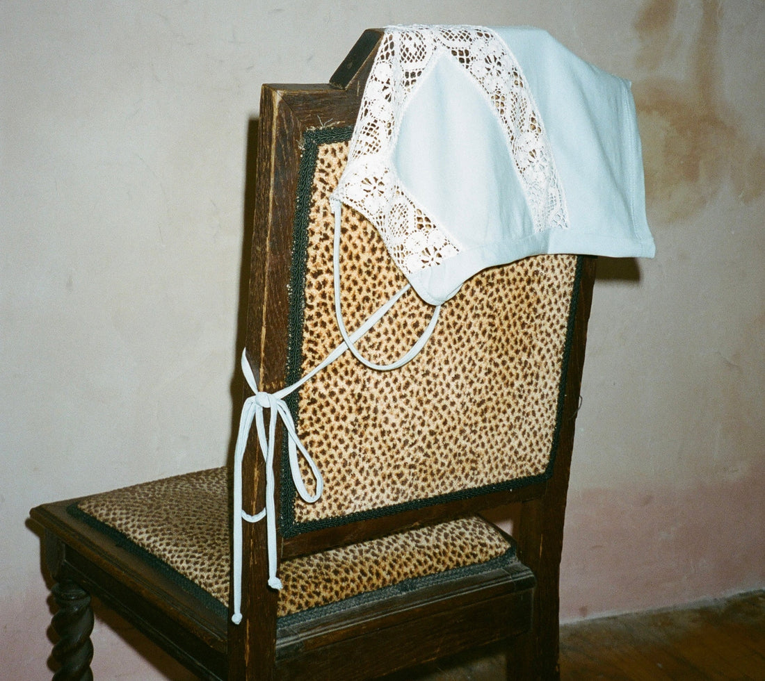 Lunetti paloma top in coastal blue with white lace trim draped on a leopard print vintage desk chair