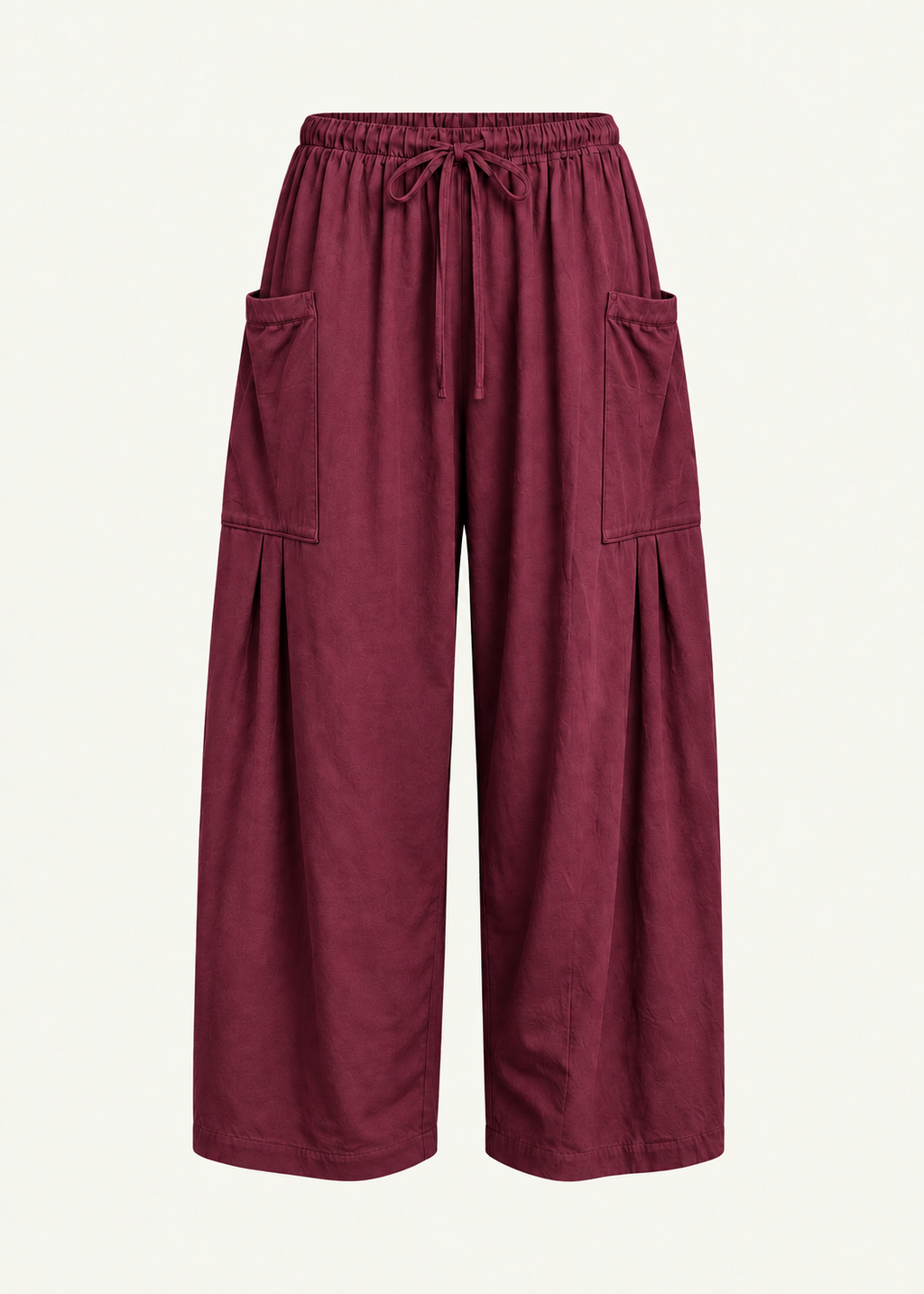 Front product view of the Rouge Bailey Pant by Lunetti against an ivory background, featuring rich burgundy bamboo cotton fabric, a relaxed wide-leg silhouette, elastic drawstring waistband, and symmetrical oversized cargo pockets with pleated detailing.