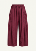 Front product view of the Rouge Bailey Pant by Lunetti against an ivory background, featuring rich burgundy bamboo cotton fabric, a relaxed wide-leg silhouette, elastic drawstring waistband, and symmetrical oversized cargo pockets with pleated detailing.
