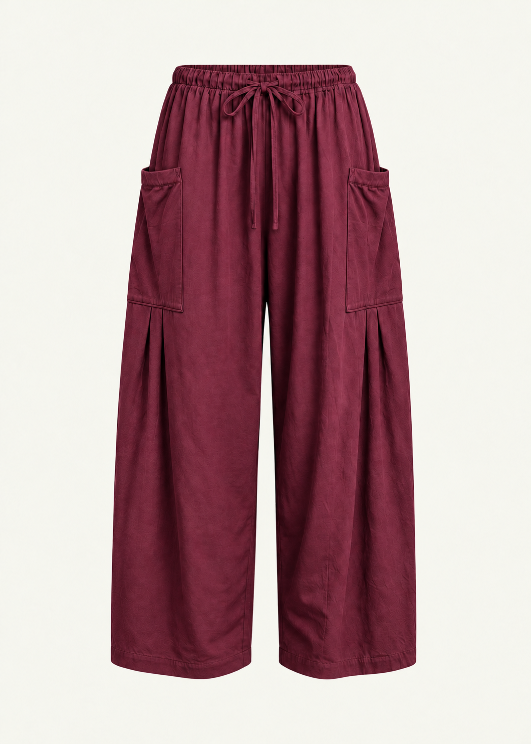 Front product view of the Rouge Bailey Pant by Lunetti against an ivory background, featuring rich burgundy bamboo cotton fabric, a relaxed wide-leg silhouette, elastic drawstring waistband, and symmetrical oversized cargo pockets with pleated detailing.