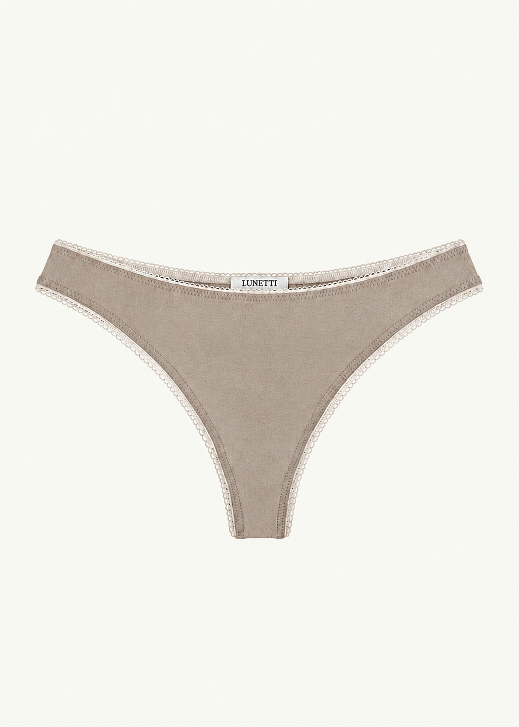 Front product view of the Stone Charlotte Thong by Lunetti against an ivory background, featuring a soft taupe hue, high-cut thong silhouette, and delicate picot trim along the waistband and leg openings.
