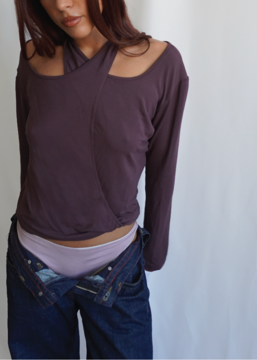 Model wearing the Amethyst Dahlia Top by Lunetti with low-rise blue jeans, styled with an asymmetric neckline and shoulder cutout to showcase the versatile four-way design.