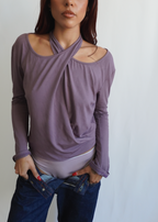 Front view of a model wearing the Orchid Dahlia Top by Lunetti with blue jeans, highlighting the softly draped asymmetric neckline and fitted long sleeves.