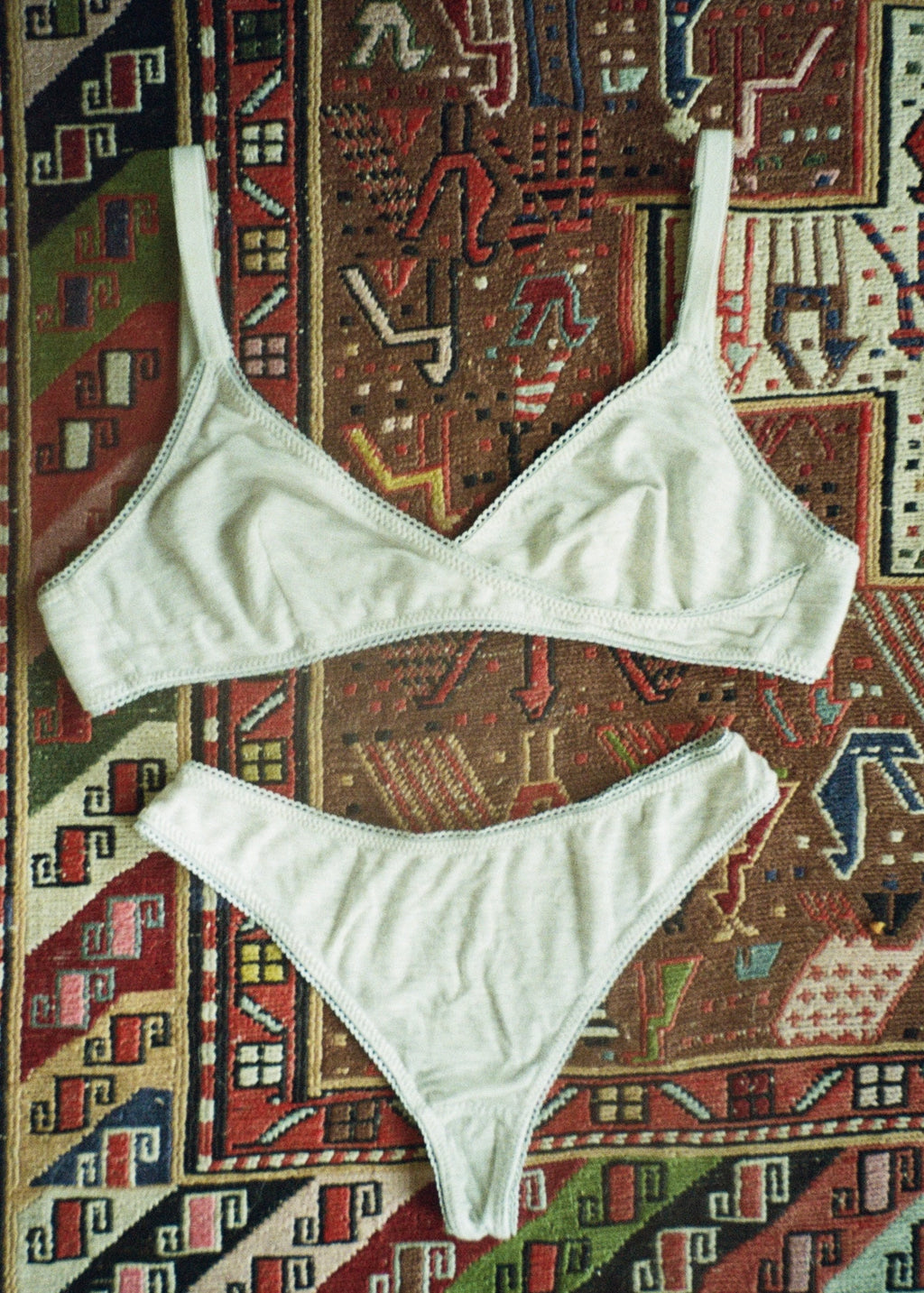 Heather grey Margot Bralette and matching thong by Lunetti arranged on a colorful vintage rug, showcasing the coordinating bamboo jersey underwear set.