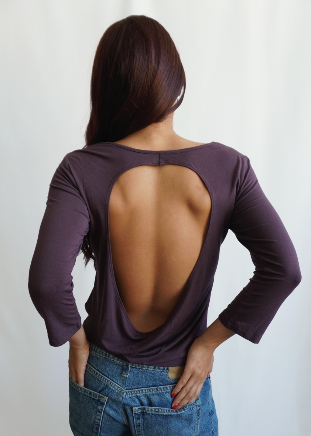 Rear view of a model wearing the Amethyst Willow Top by Lunetti with blue jeans, highlighting its deep open-back design and softly draped bamboo jersey fabric.