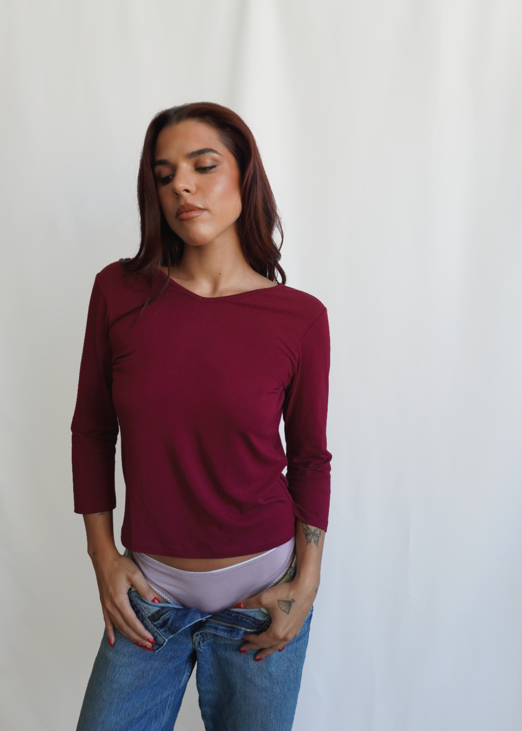 Model wearing the Merlot Willow Top by Lunetti with blue jeans, featuring a V-neckline, relaxed fit, and three-quarter sleeves.