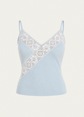 A light blue camisole top with thin straps and a diagonal white lace panel across the chest, shown on a plain light beige background.