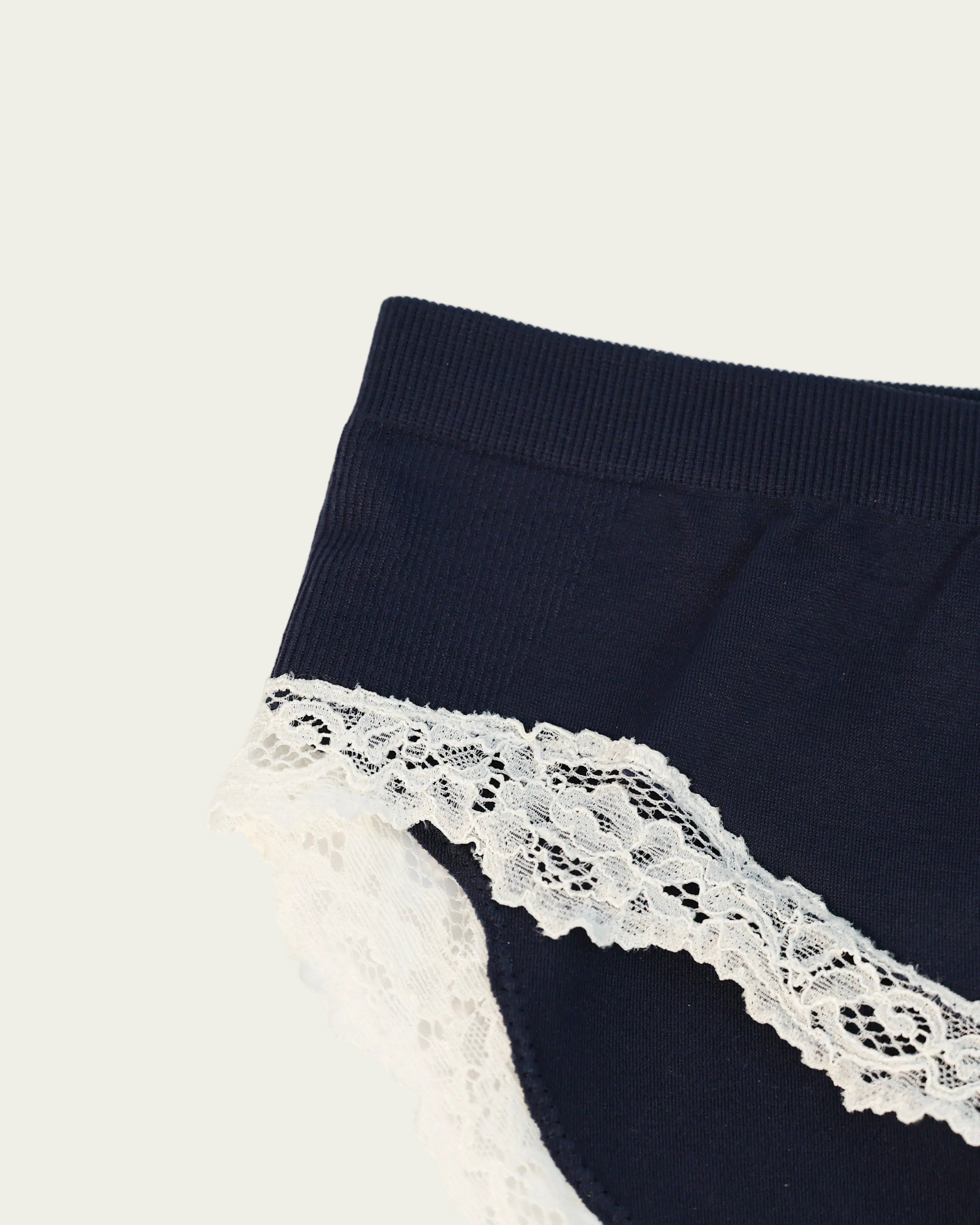 Close-up detail of the Luna Brief in Midnight Navy featuring delicate white lace trim and a ribbed waistband.