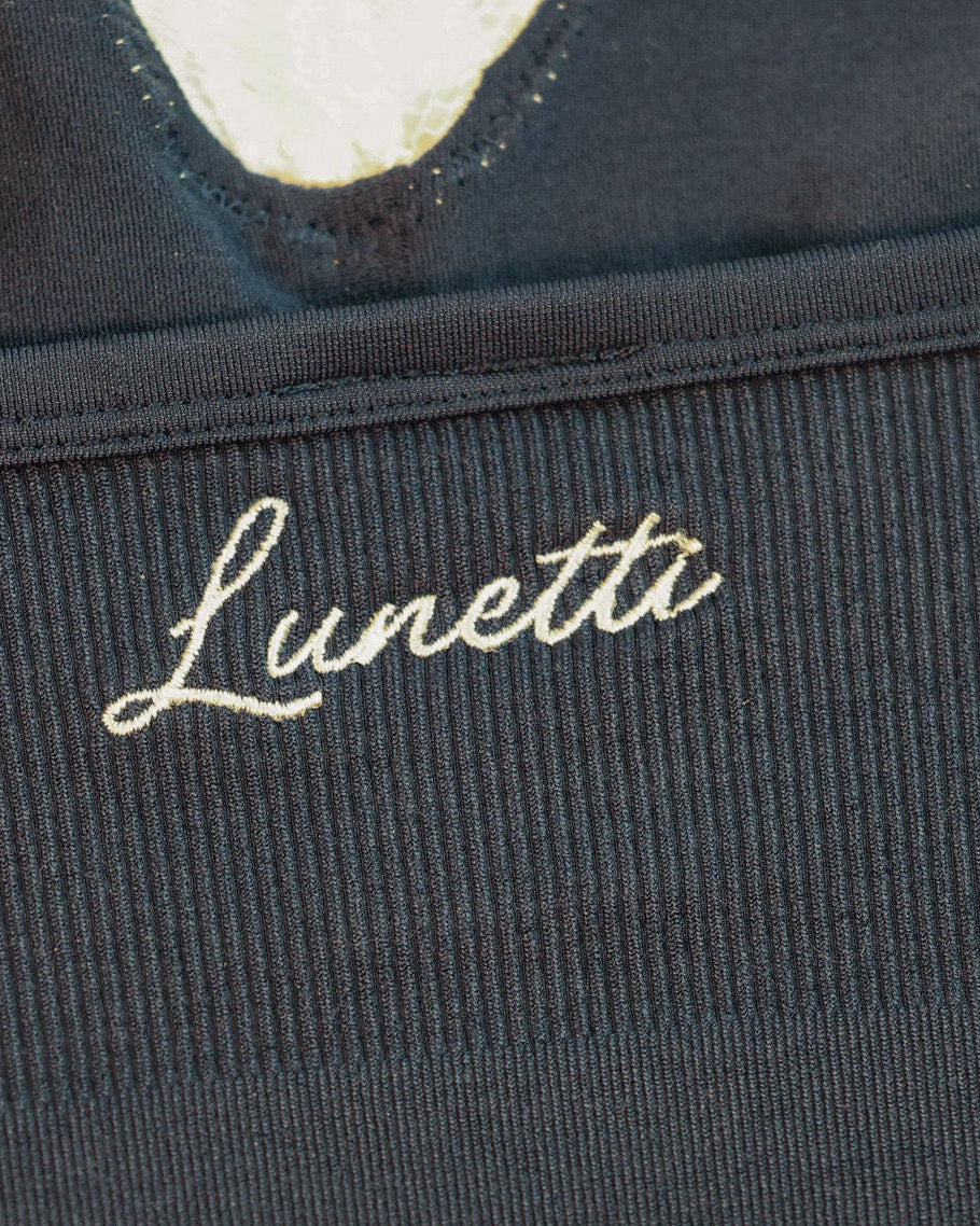 Close-up detail of the white Lunetti embroidery on the ribbed waistband of the Luna Top in Midnight Navy.